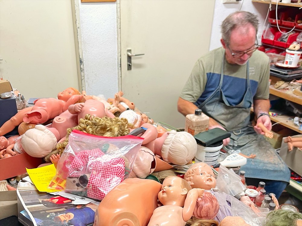 Christian arbeitet am Werkstatttisch voller Puppen und Puppenteile